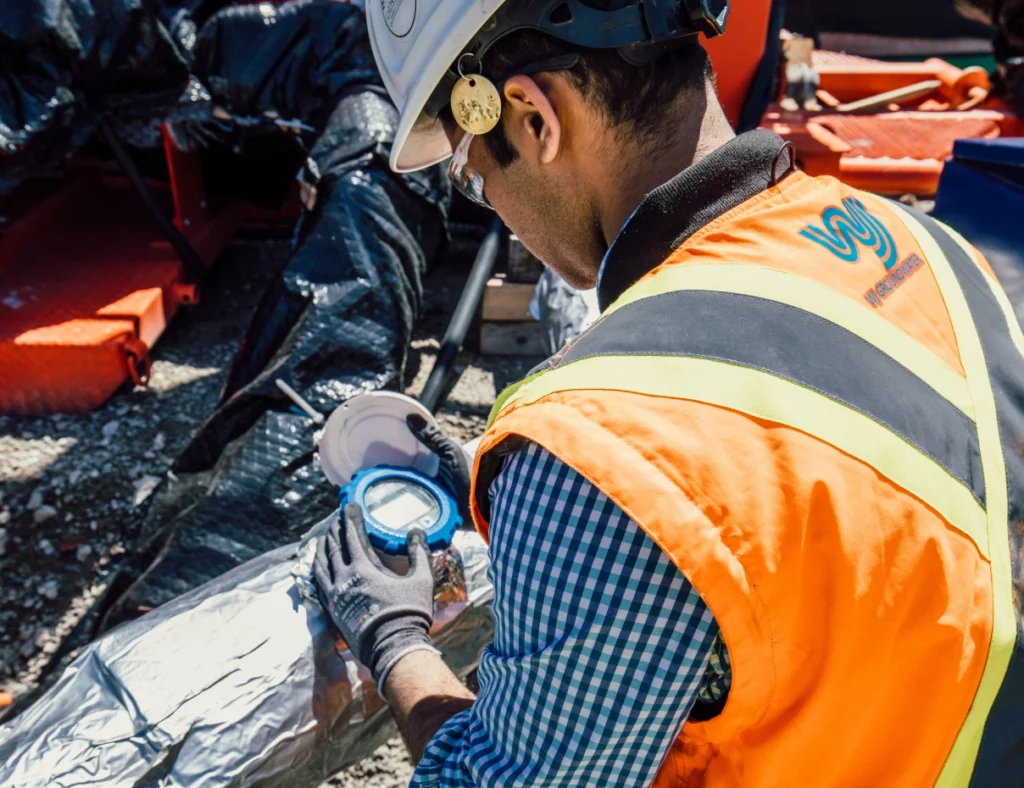 Worker inspecting equipment on site as part of groundwater treatment service.